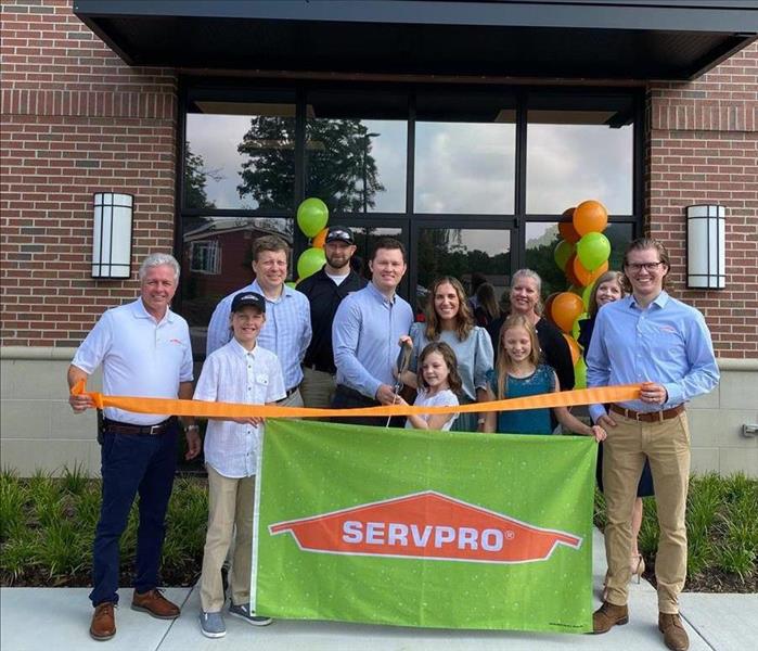 servpro employees posted in front of building with ribbon to cut
